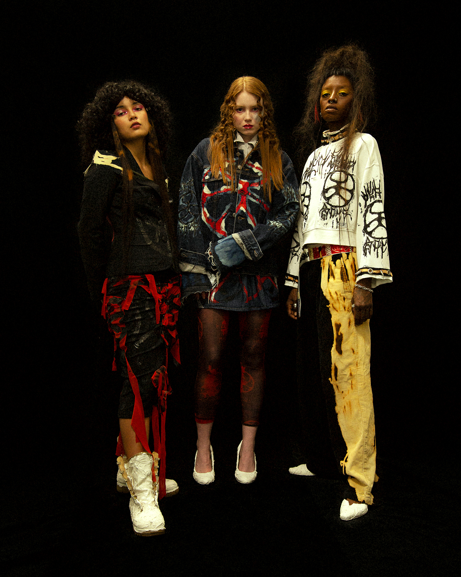 Full body photo of three models facing the camera on a black background